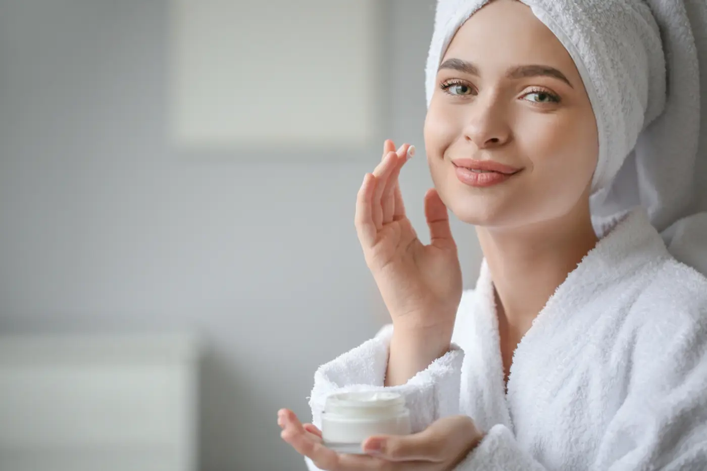 Woman in a bathrobe caring for her smooth skin