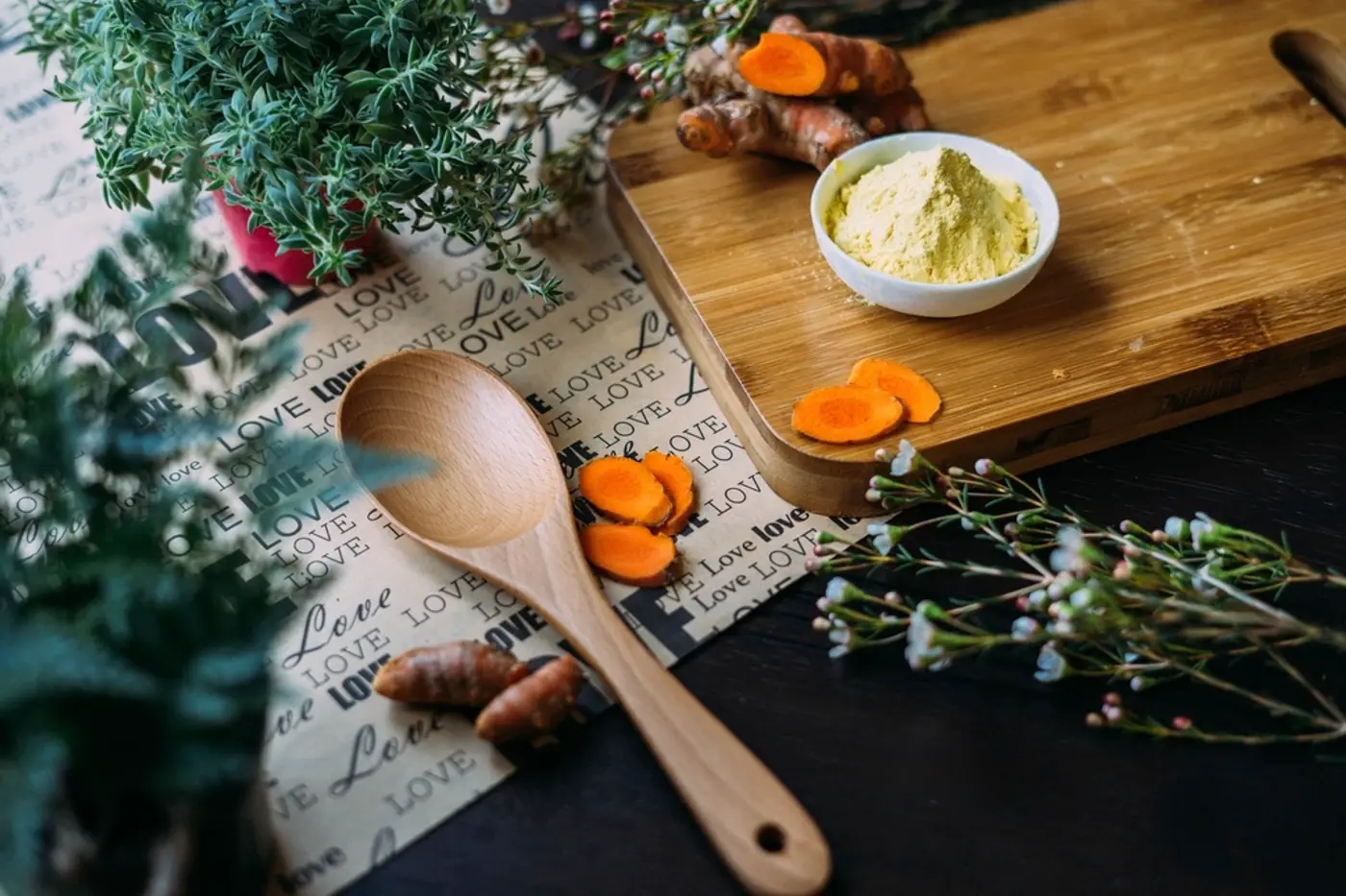Fresh turmeric, gram flour and herbs on a wooden board