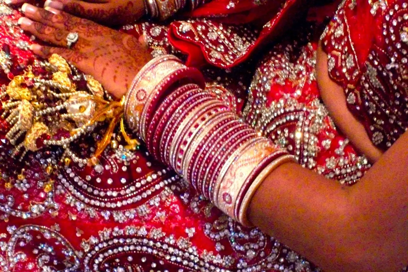 Wedding guest in a red sari with bangles and henna